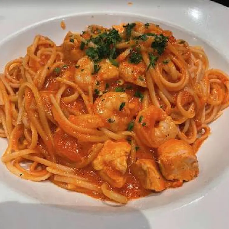 red sauce spaghetti served with some shrimps on the top in a white plate